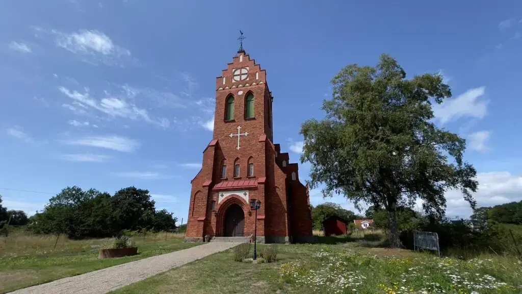 Aspö kyrka i rött tegel med tornet mot blå himmel