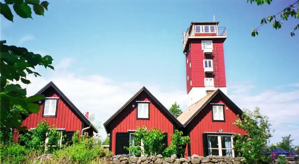 Aspö lotstorn i rött med tre röda hus framför
